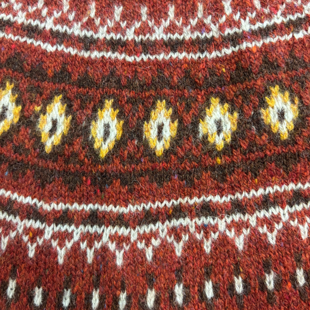Close-up of a patterned fabric with red, yellow, and white colors.
