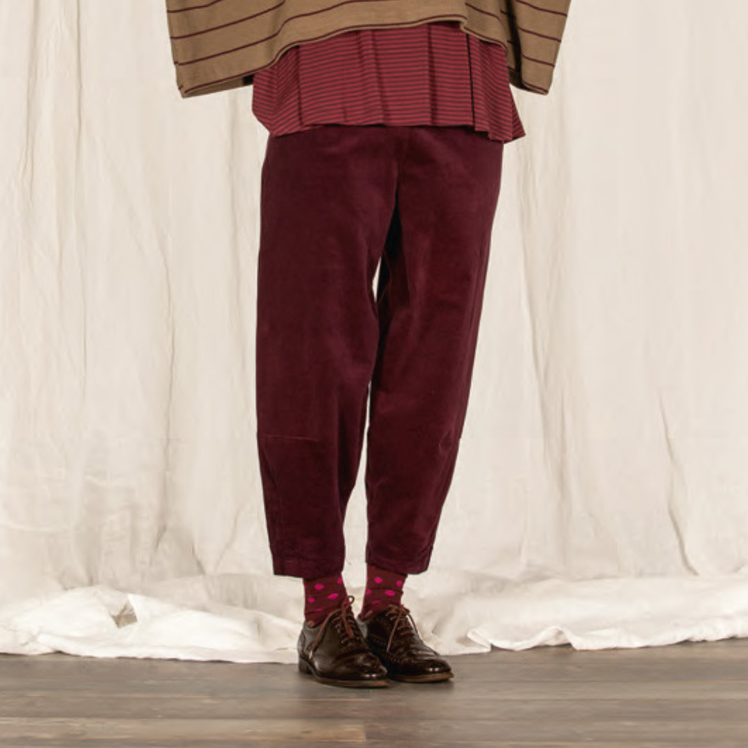 Burgundy corduroy pants with a slightly loose, tapered fit.  The pants are shown worn with dark brown oxfords.