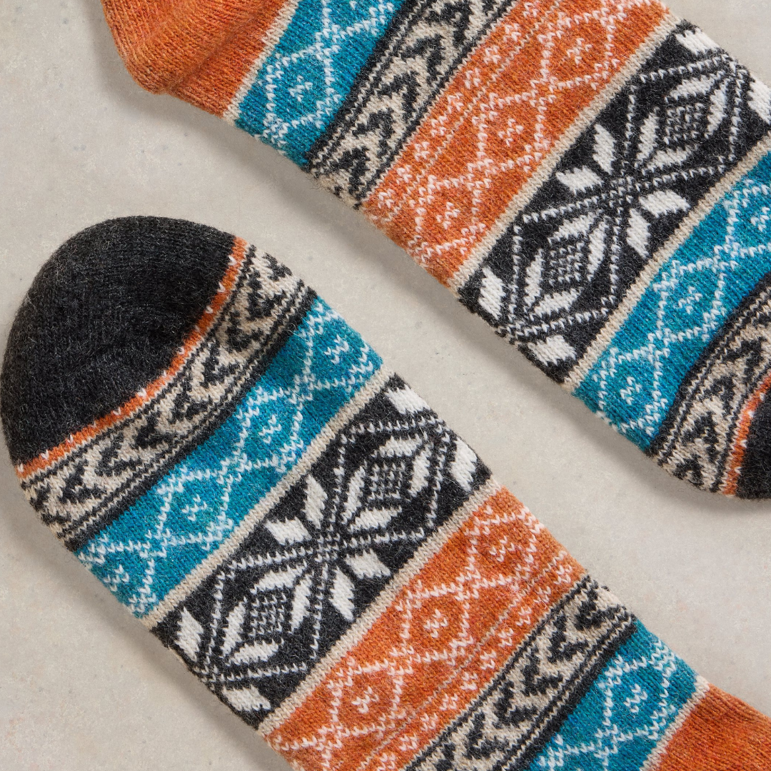 Pair of wool socks with teal, orange, black, and white geometric Fair Isle pattern.