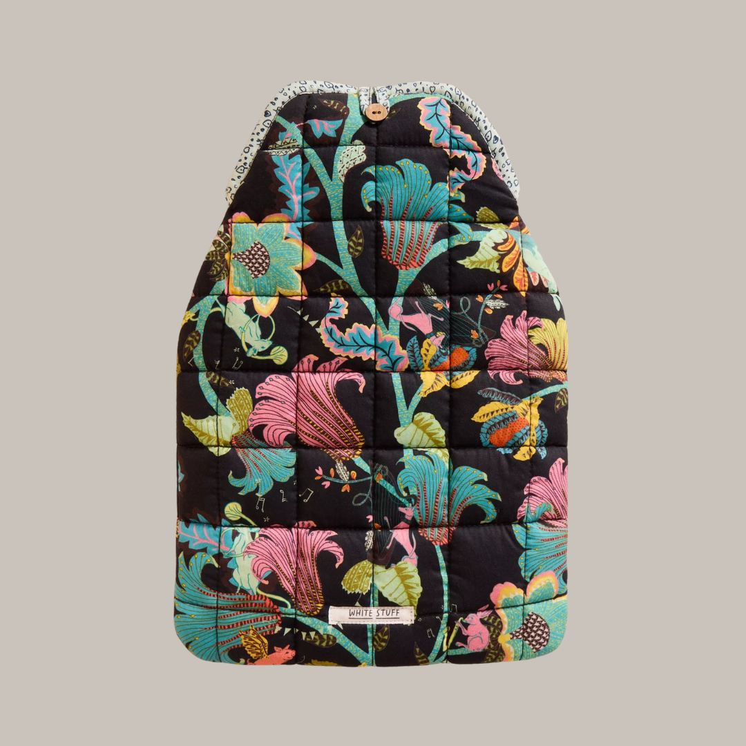 Black quilted hot water bottle with a vibrant floral print featuring teal, pink, and green flowers on a dark background.