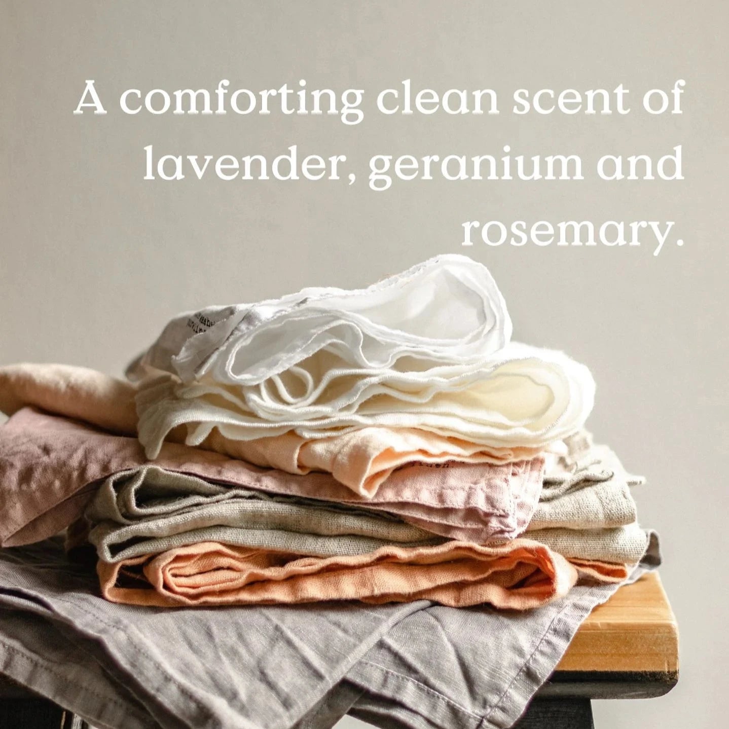 Stack of linen cloths in various pastel shades, including white, beige, peach, and gray.