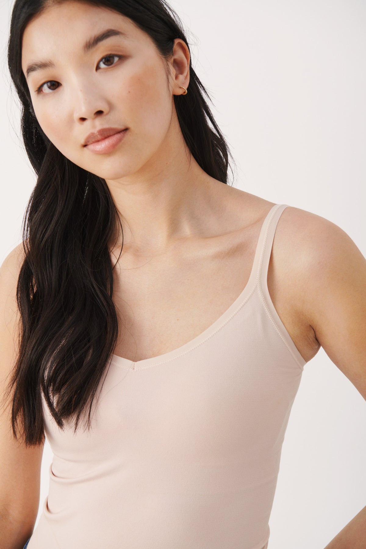 Woman wearing a beige tank top against a plain background