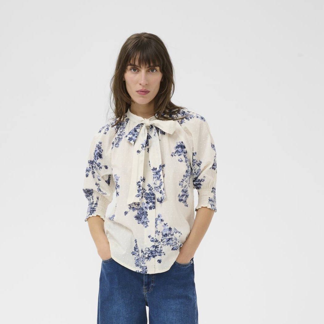 Woman wearing a floral blouse and blue jeans on a white background