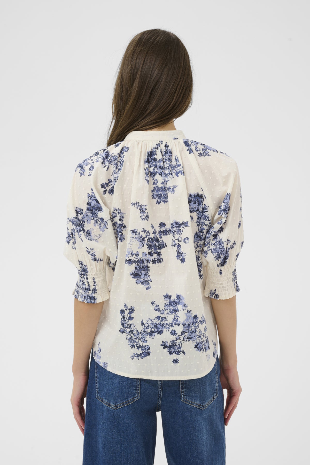 Woman wearing a floral blouse with blue flowers on a white background