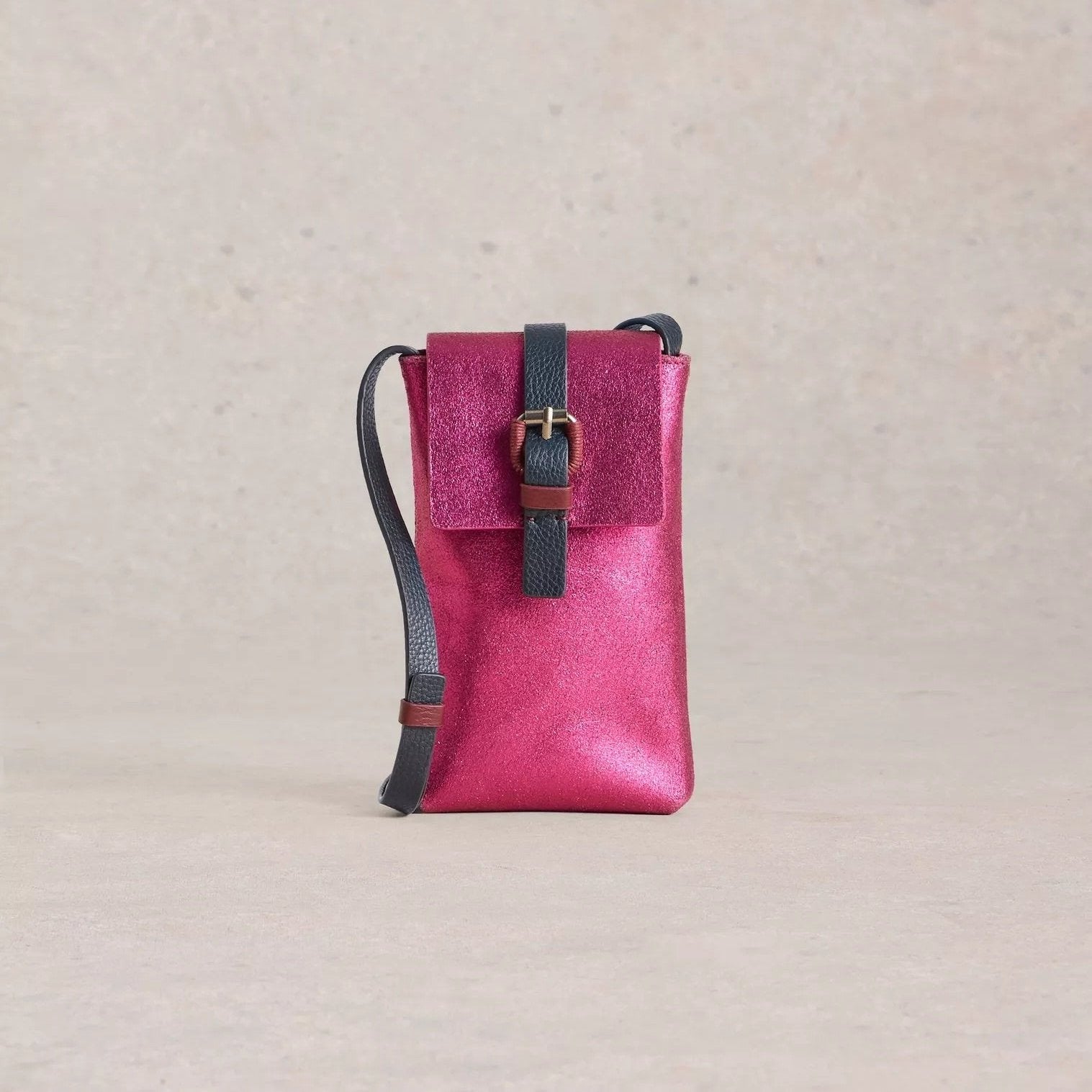 Pink metallic leather crossbody bag with a dark navy strap and buckle closure.