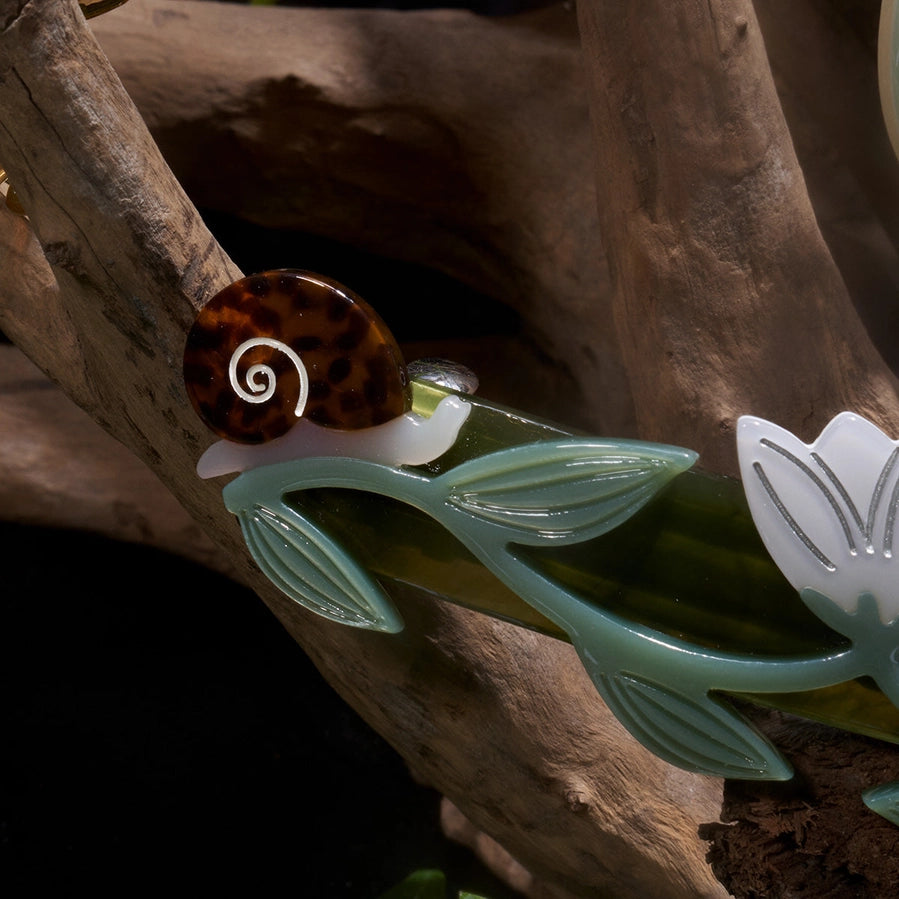 Decorative hair clip with a snail design on a wooden background