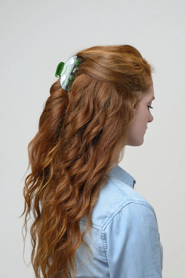Woman with long wavy hair wearing a green headband against a plain background
