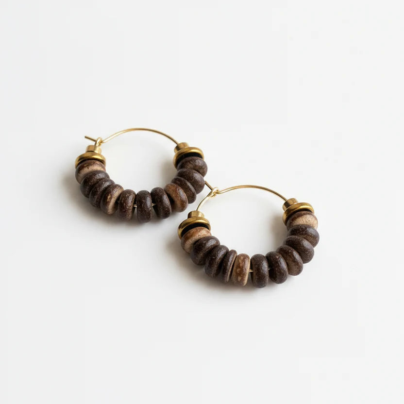 Pair of hoop earrings with brown beads and gold accents on an off white background