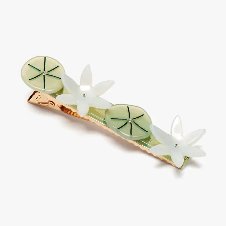 A hair claw clip decorated with three white flower charms and two light green oval medallions with green starburst details, set on a rose gold metal base against a light gray background.