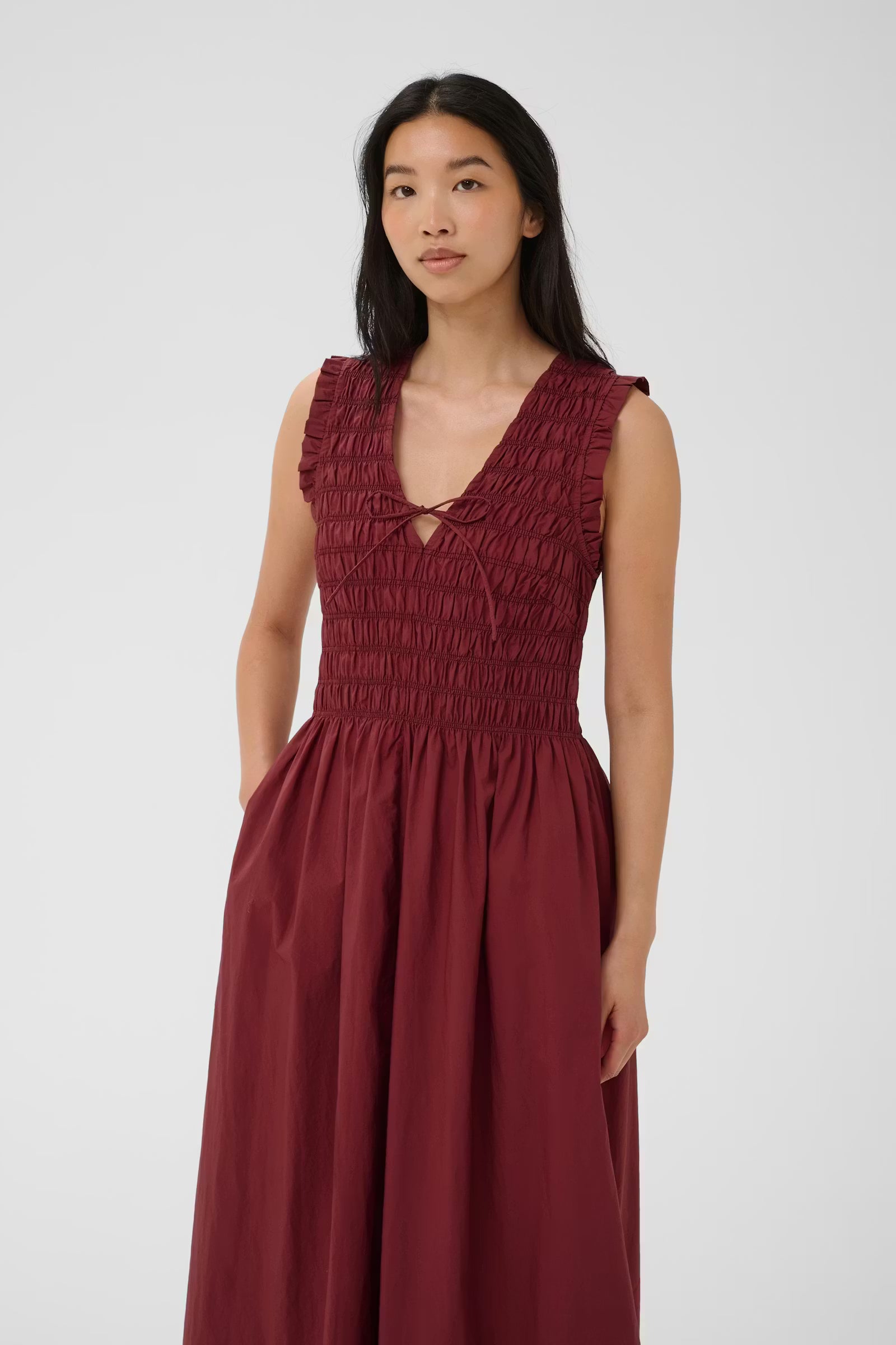 Woman wearing a burgundy dress against a white background