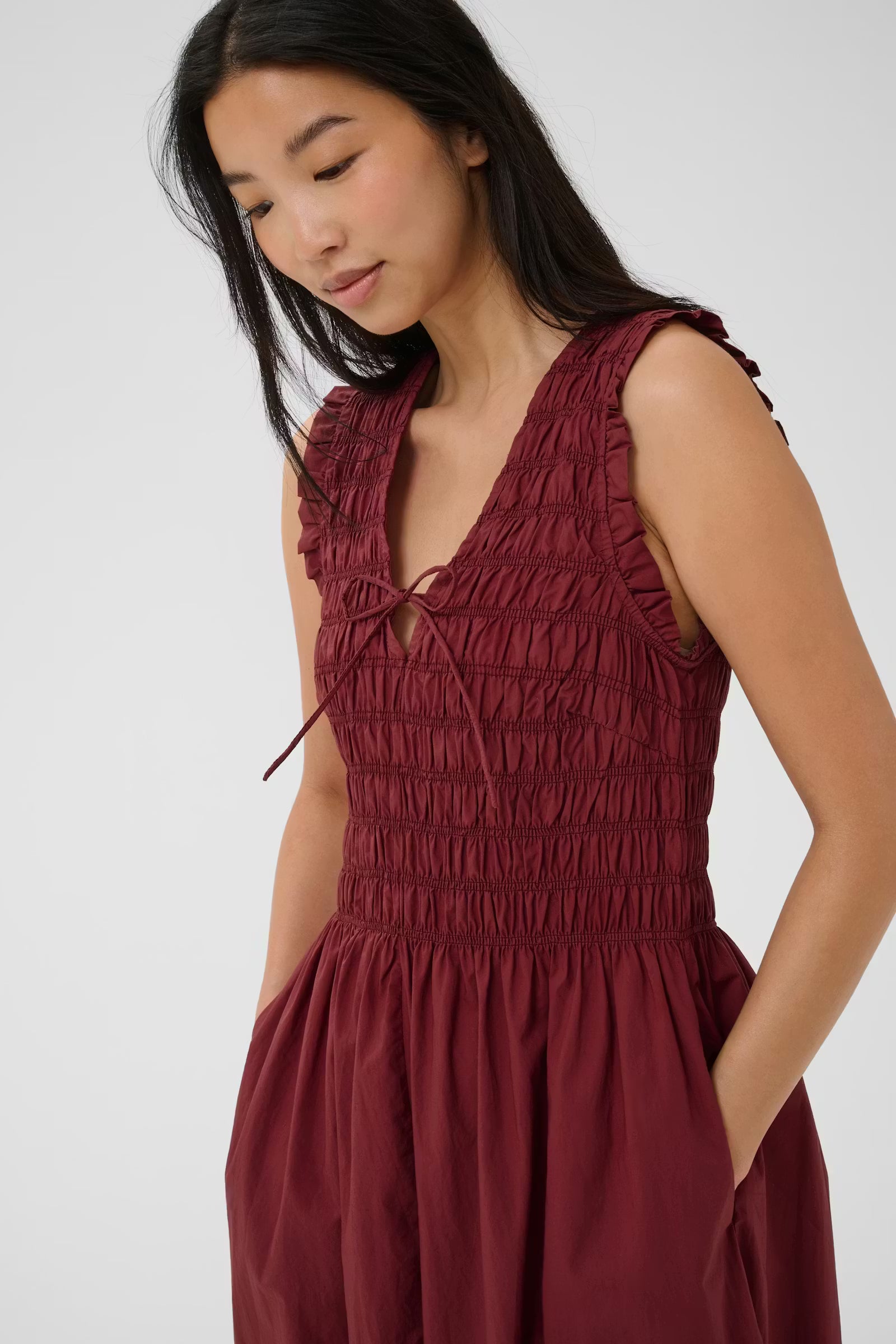 Woman wearing a burgundy dress with a white background