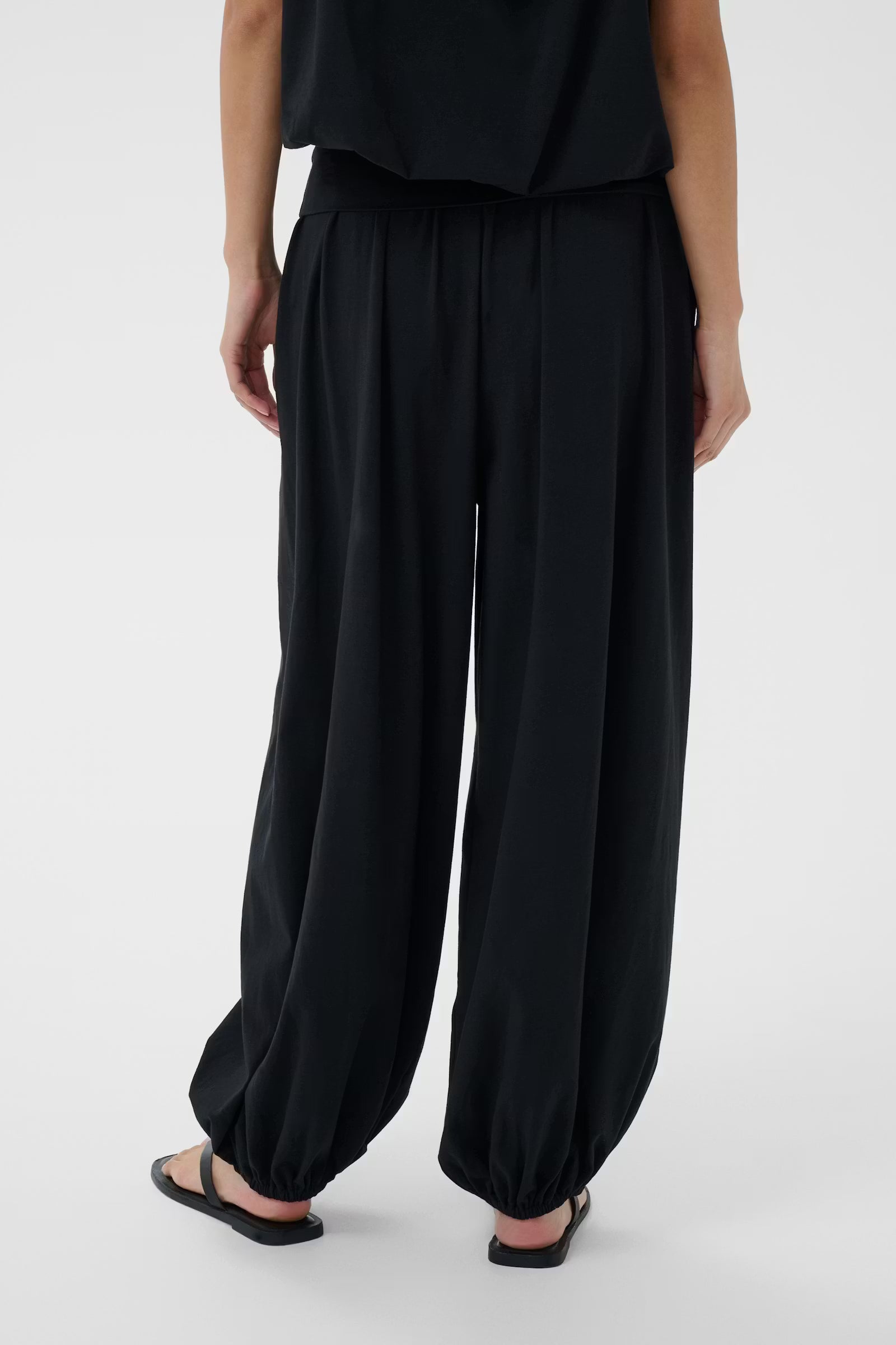 Person wearing black wide-leg pants on a white background