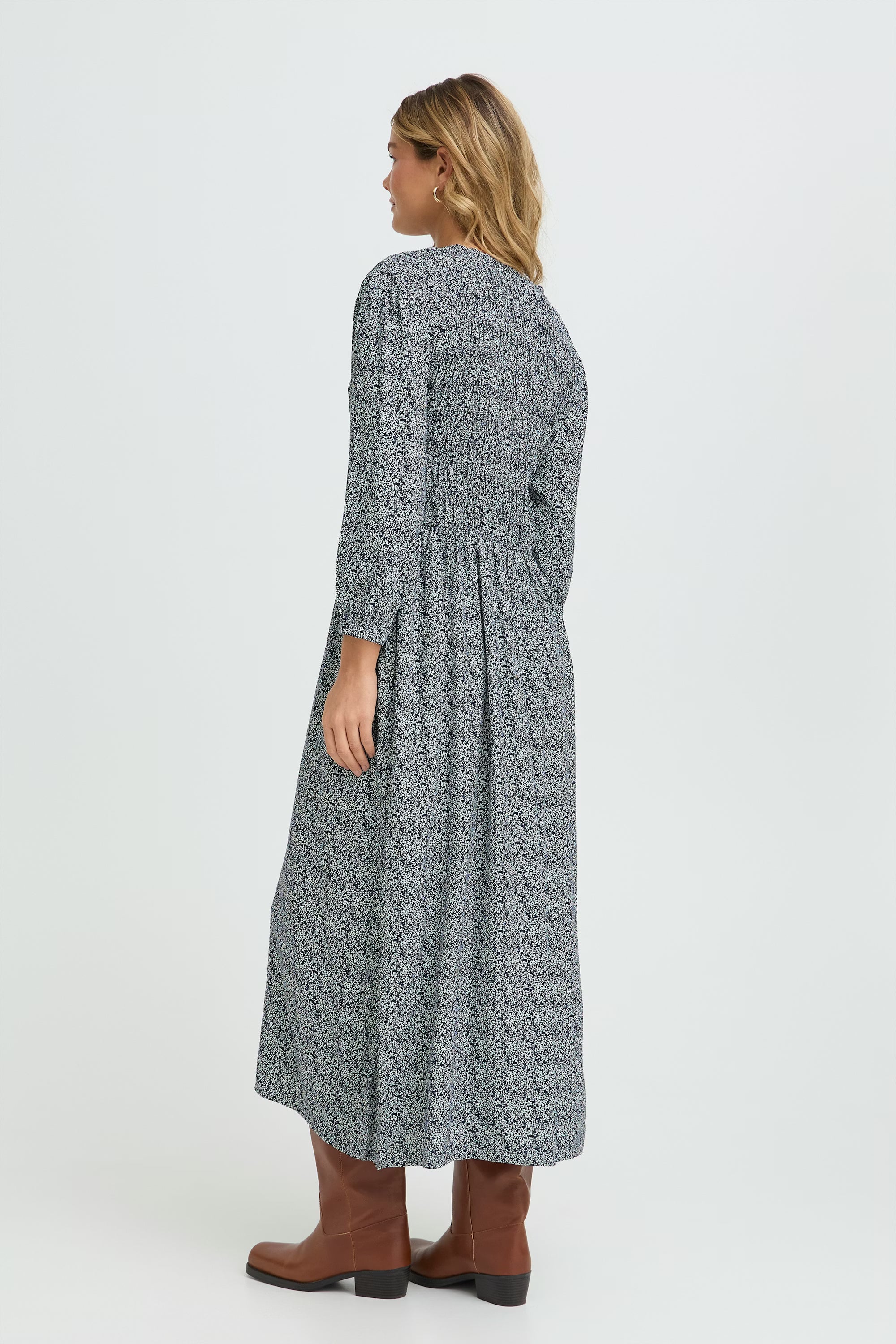 Woman wearing a long, patterned dress on a white background