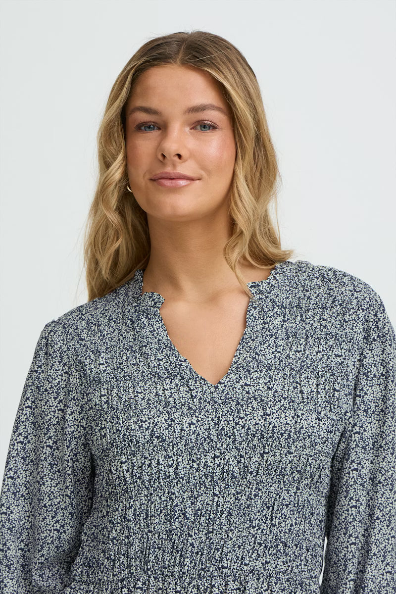 Woman wearing a blue floral dress against a white background