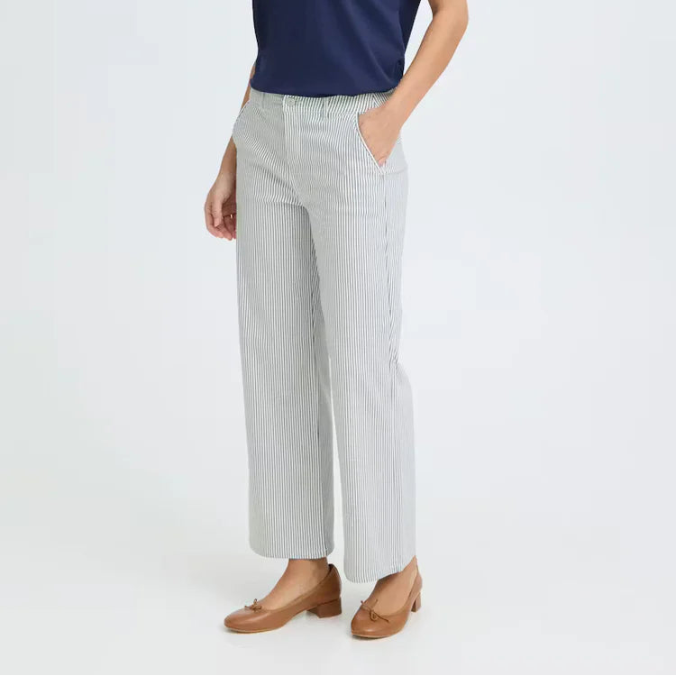 Woman wearing a navy blue top and light gray pants on a white background