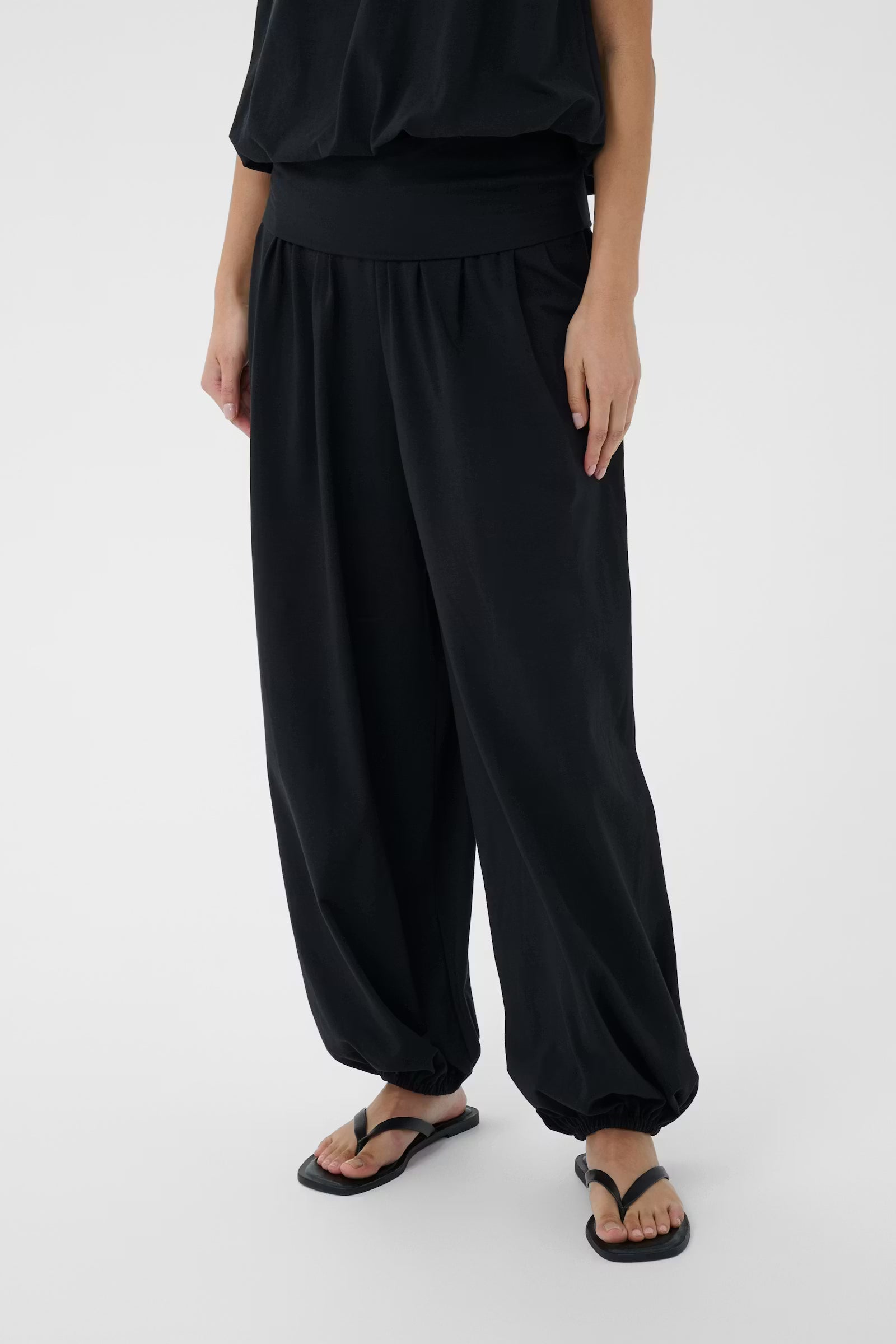 Person wearing black wide-leg pants and a black top on a white background