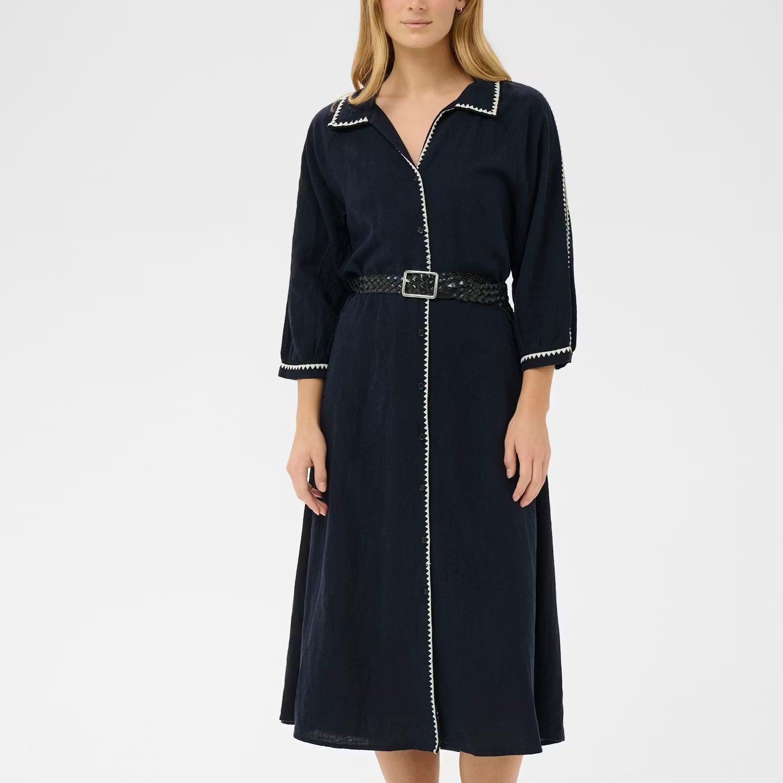 Woman wearing a navy dress with white trim on a white background