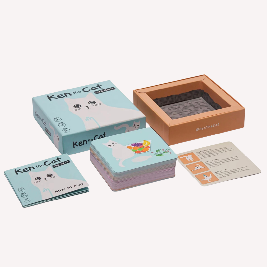 Ken the Cat board game set with a light blue illustrated box, an open peach-colored storage box, a stack of cards, and a single instruction card on a plain light background.
