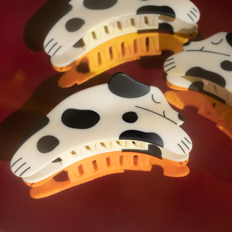 Three hair clips with a polka dot dog pattern sit on a red background