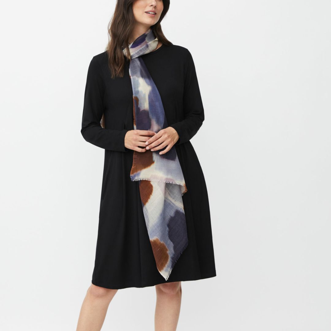 Woman wearing a black coat with a patterned scarf on a white background