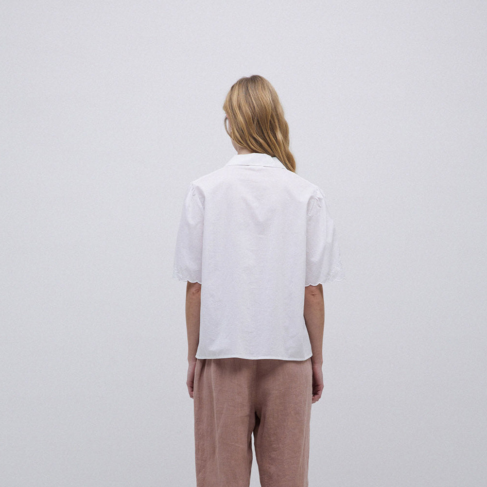 White eyelet-trimmed short-sleeve collared blouse, viewed from the back.
