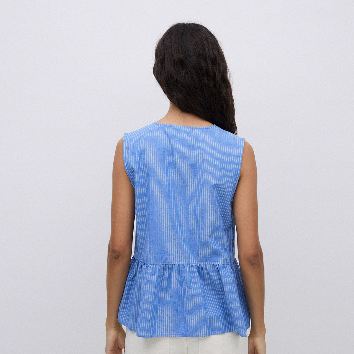 Blue sleeveless peasant top with thin white stripes and a ruffled hem.