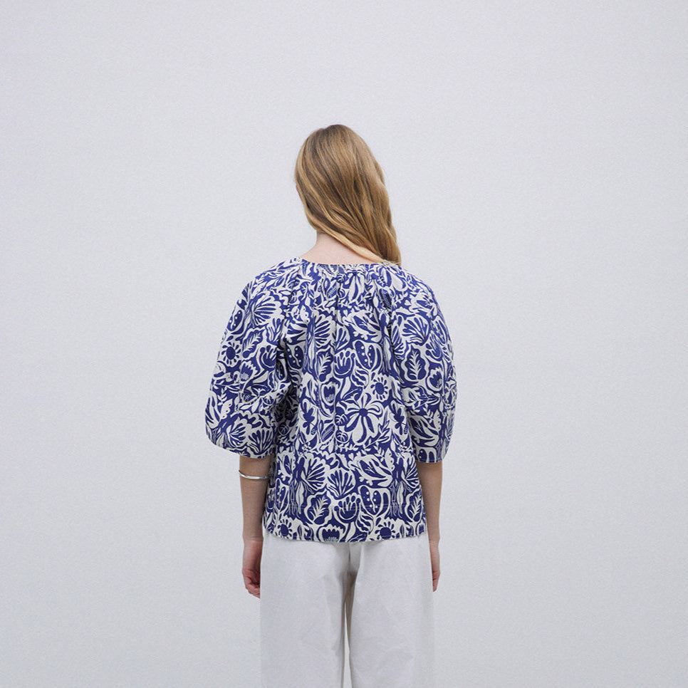 Women's blue and white floral print blouse with three-quarter sleeves and a gathered neckline.