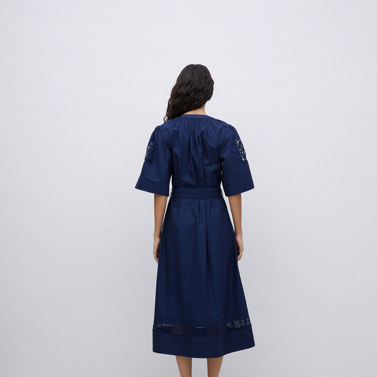 Navy midi dress with short sleeves, eyelet detailing at shoulders and hem, and a belted waist.