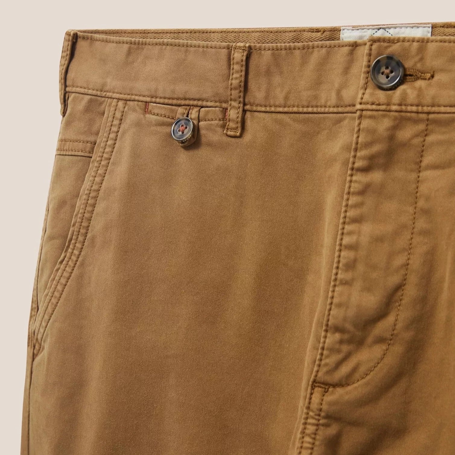 Close-up of brown twill cotton pants; visible details include waistband, pockets, and button closure.