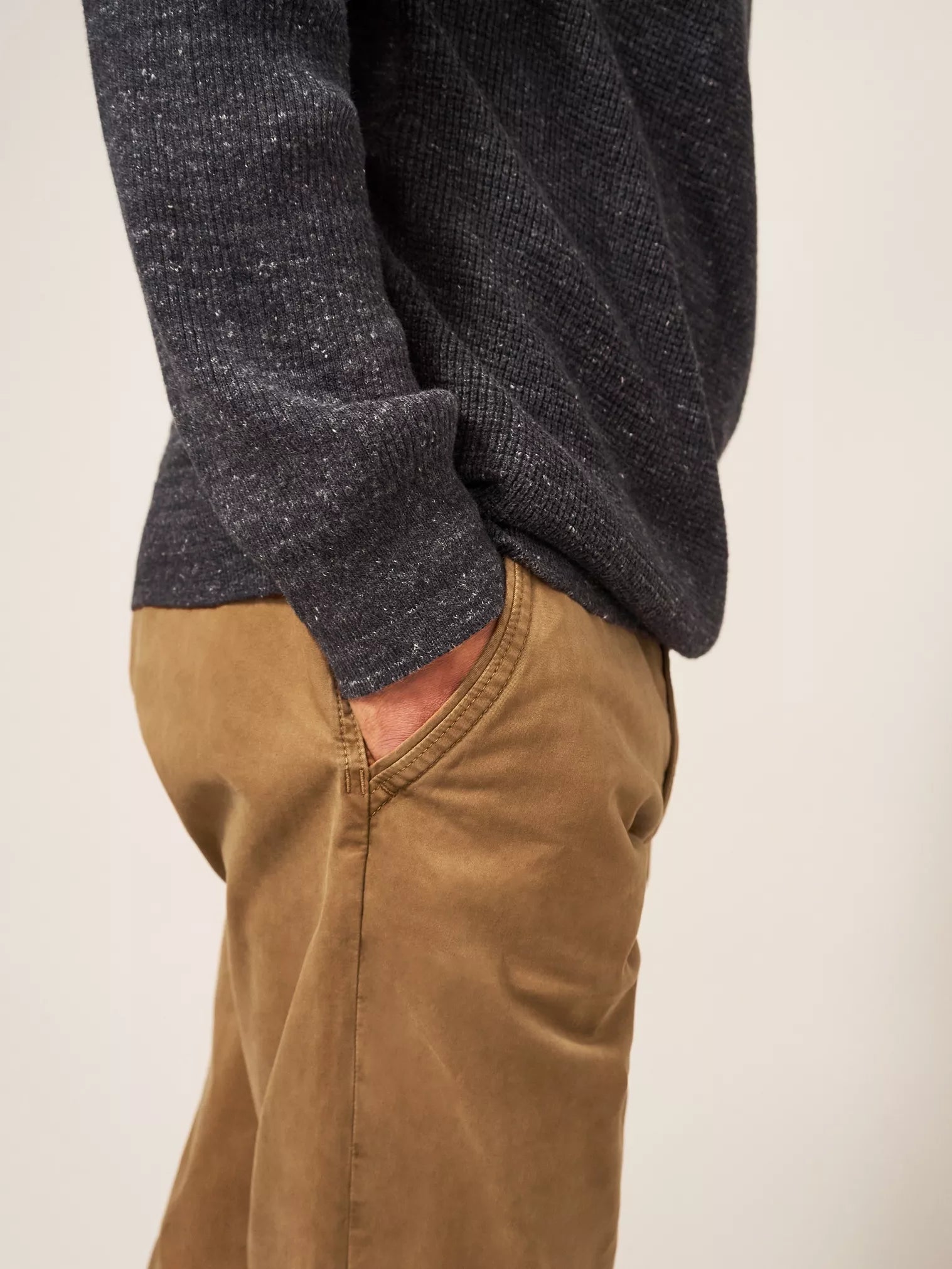Dark gray melange knit sweater with ribbed texture, partially visible over tan chinos.