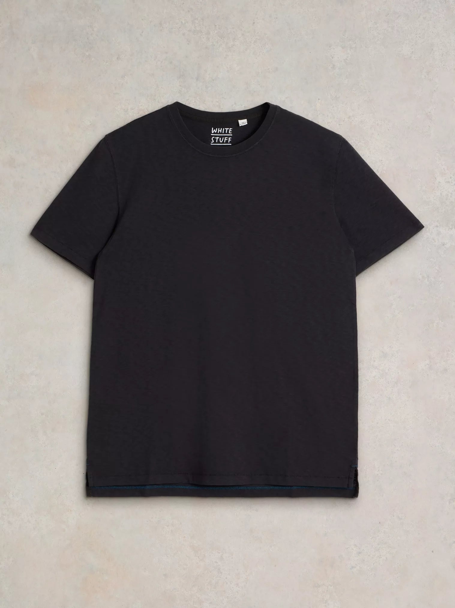 Black crew-neck short-sleeve t-shirt with a subtle teal stitch detail at the hem and "WHITE STUFF" label at the neckline.