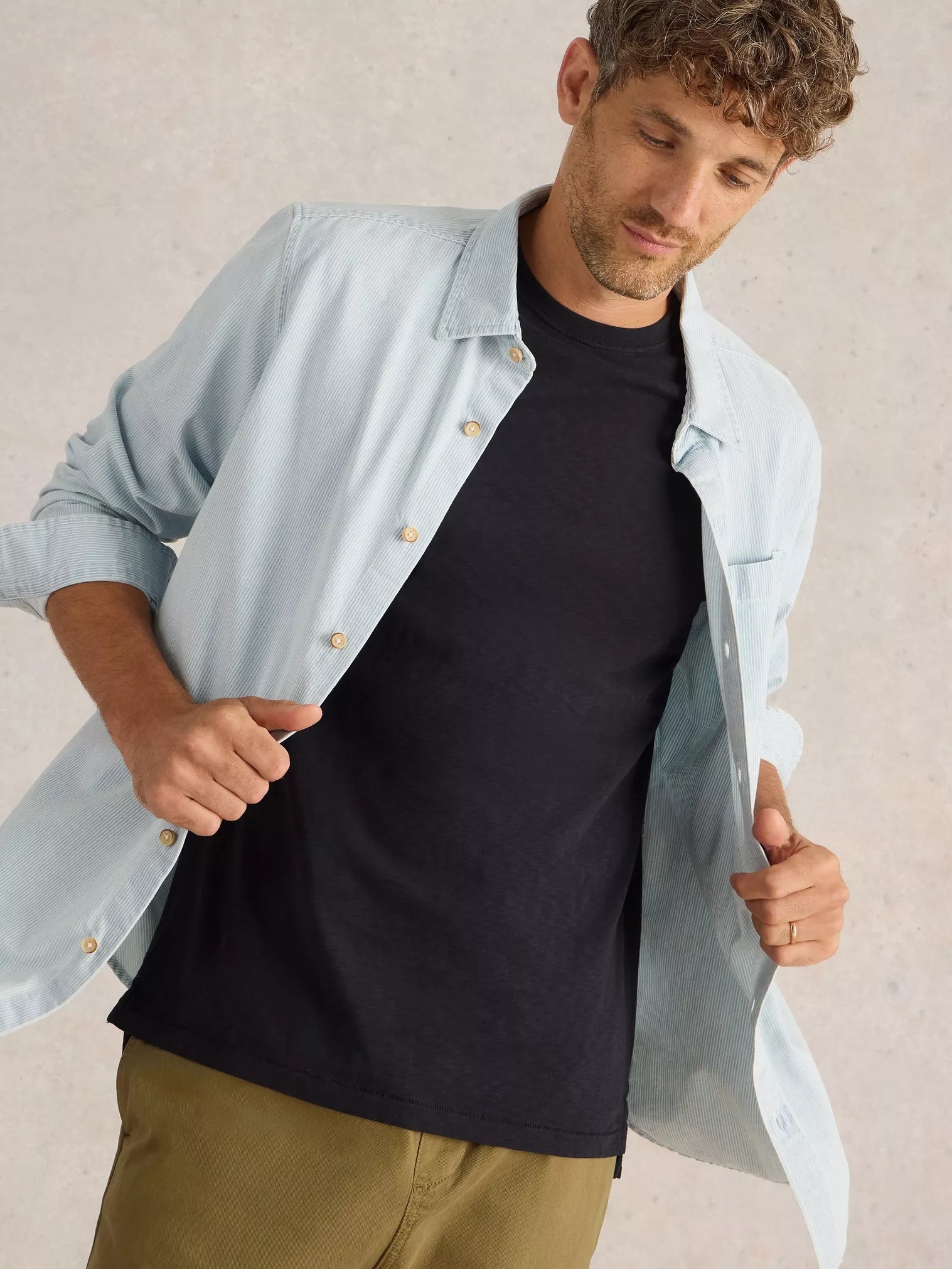 Light blue pinstripe button-down shirt layered over a black crew-neck t-shirt.