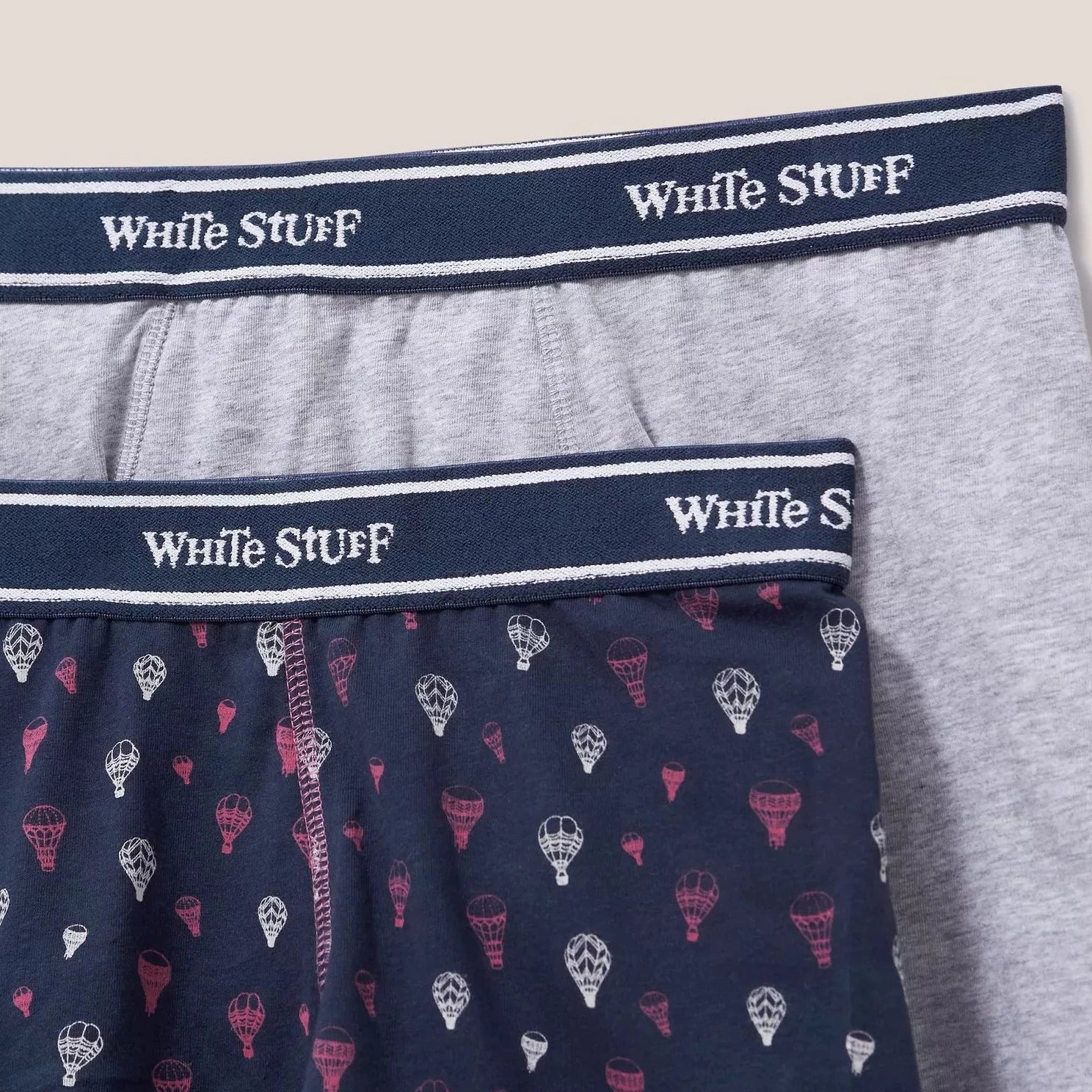Two pairs of men's boxer shorts; one grey, one navy with a hot air balloon pattern.