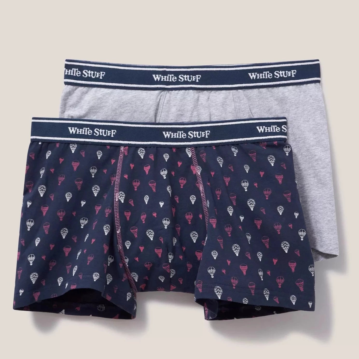 Two-pack men's boxer shorts. One pair is navy with a repeating hot air balloon pattern; the other is gray.