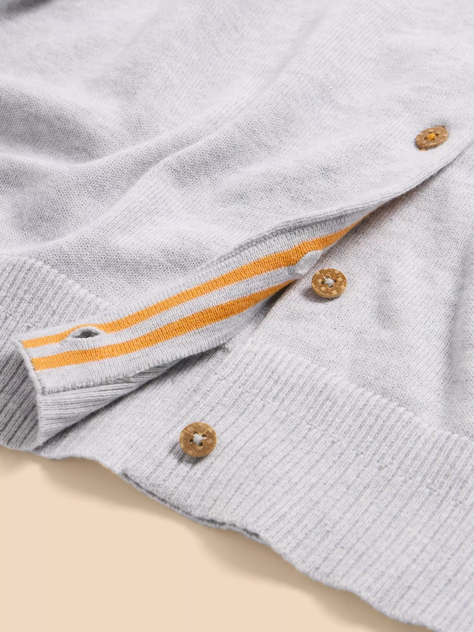 Light gray knit cardigan with orange striped detailing and wooden buttons.