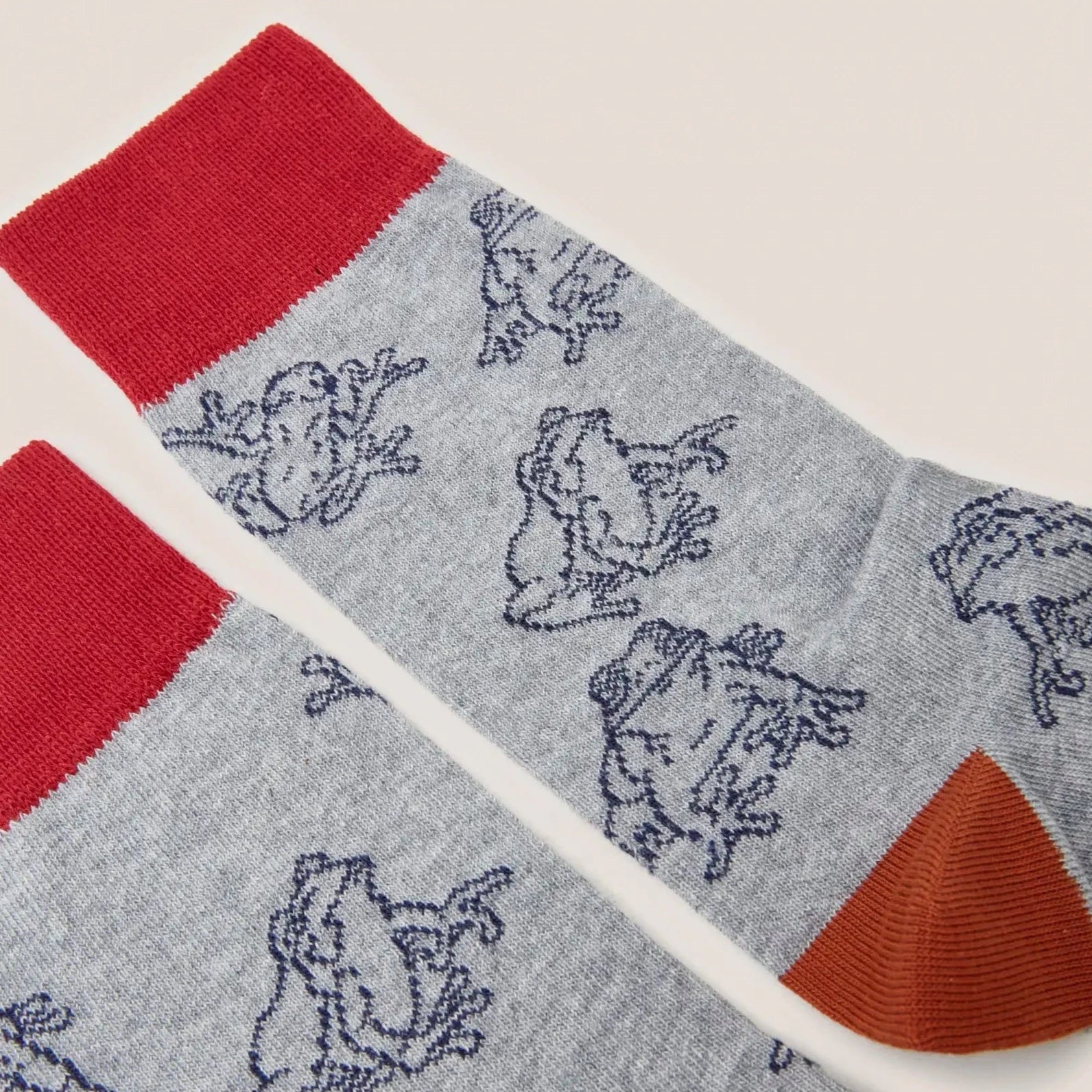 Grey crew socks with a red and rust colored cuff, featuring a repeating pattern of dark blue frogs.