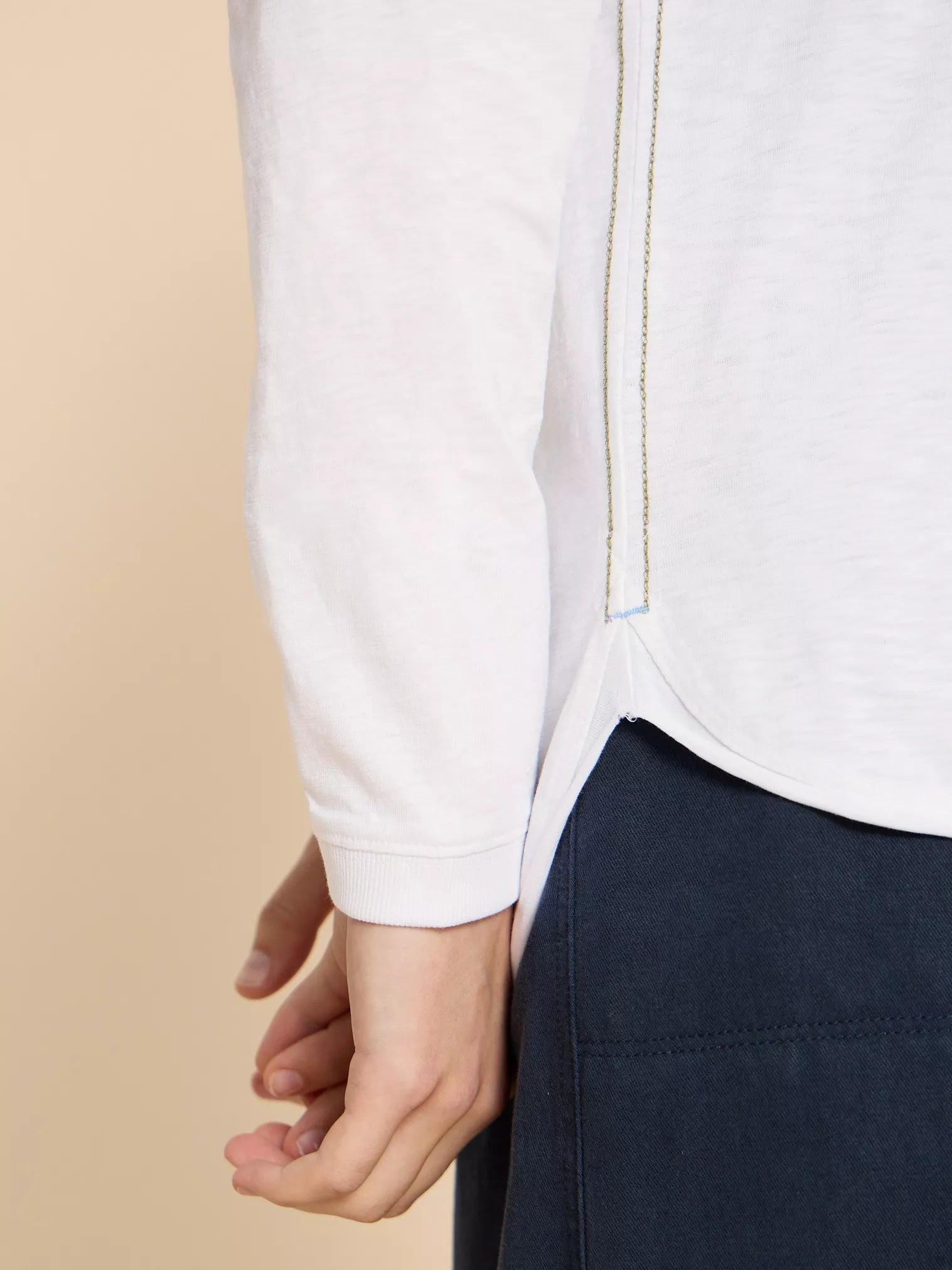 White long-sleeve shirt with gold chain detailing at the side seams and a curved hem.