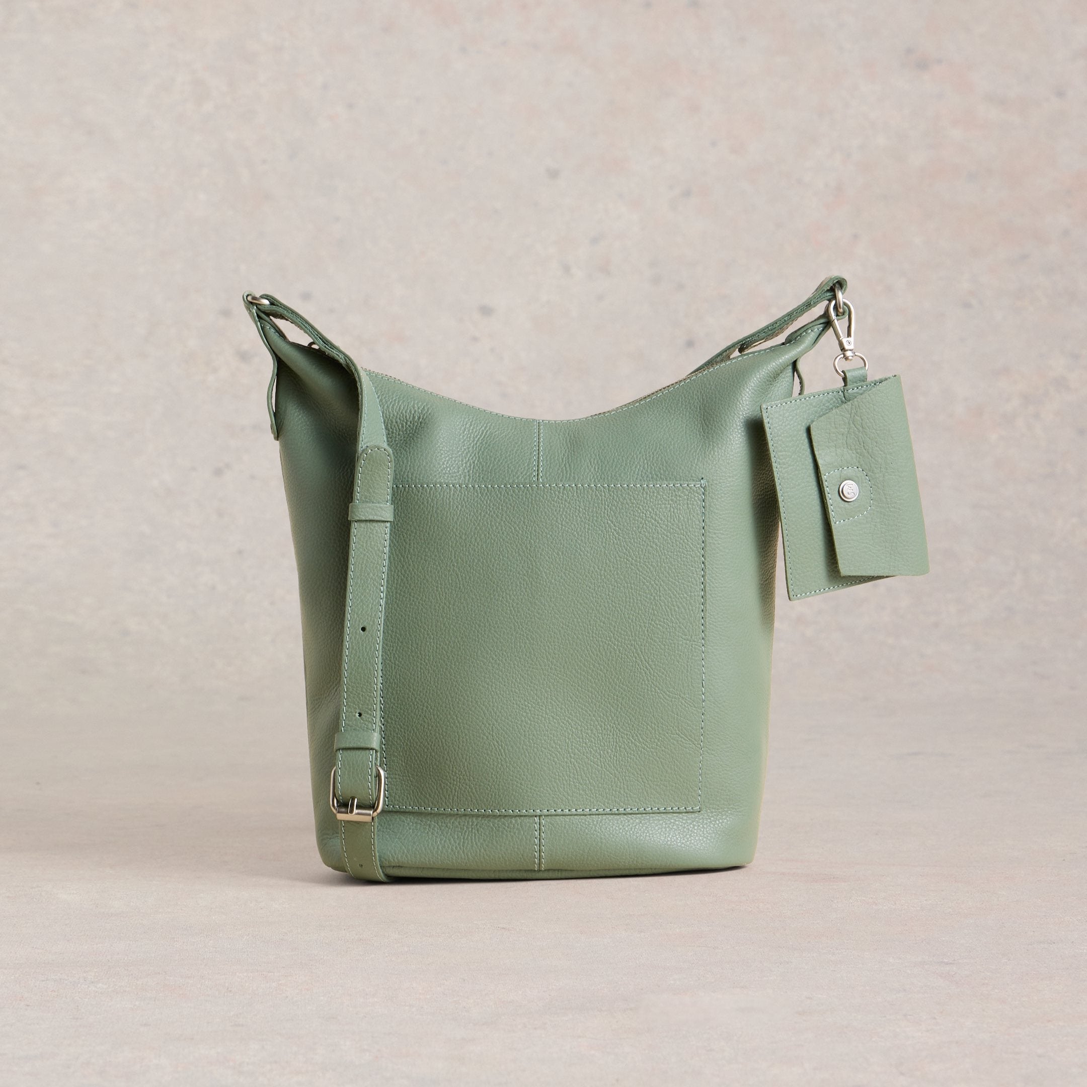 Green leather handbag with a tag on a beige background