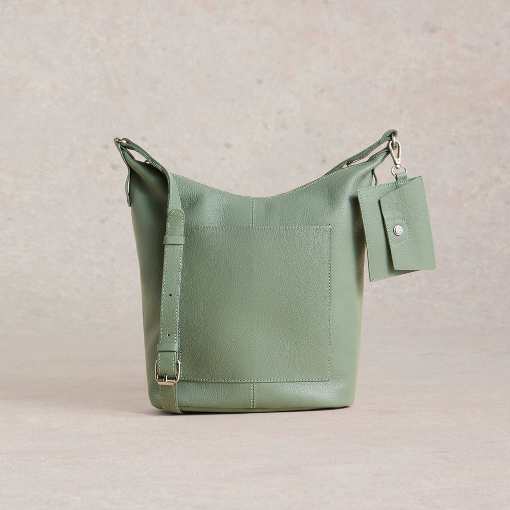 Green leather handbag with a tag on a beige background