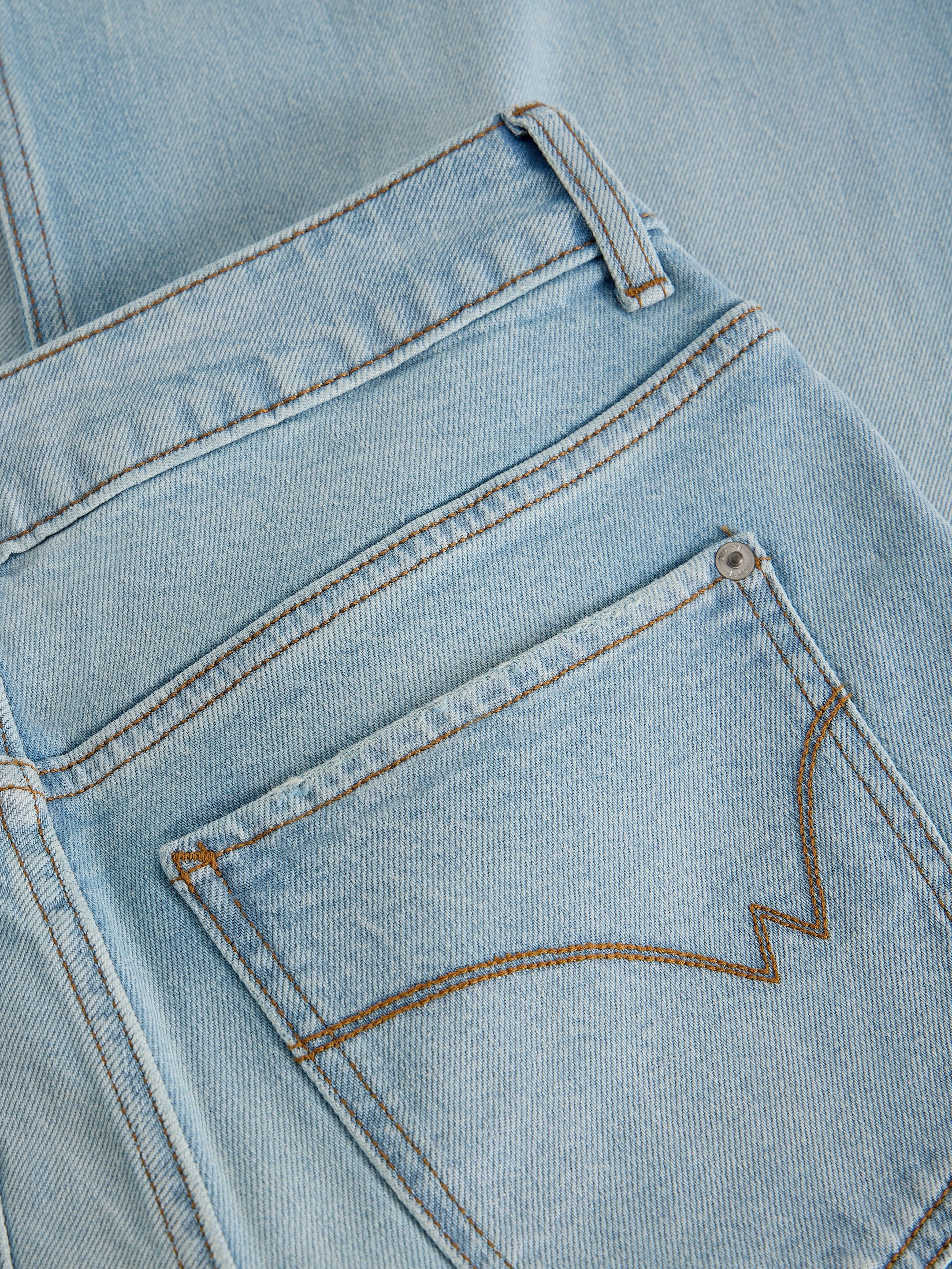 Close-up of light blue denim fabric with stitching details