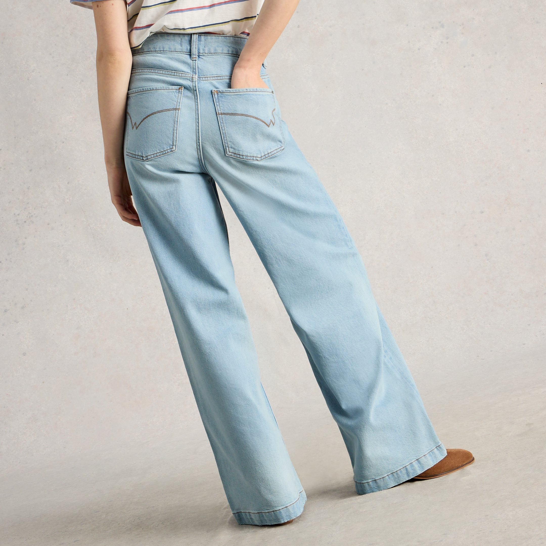 Light blue jeans worn by a person on a plain background