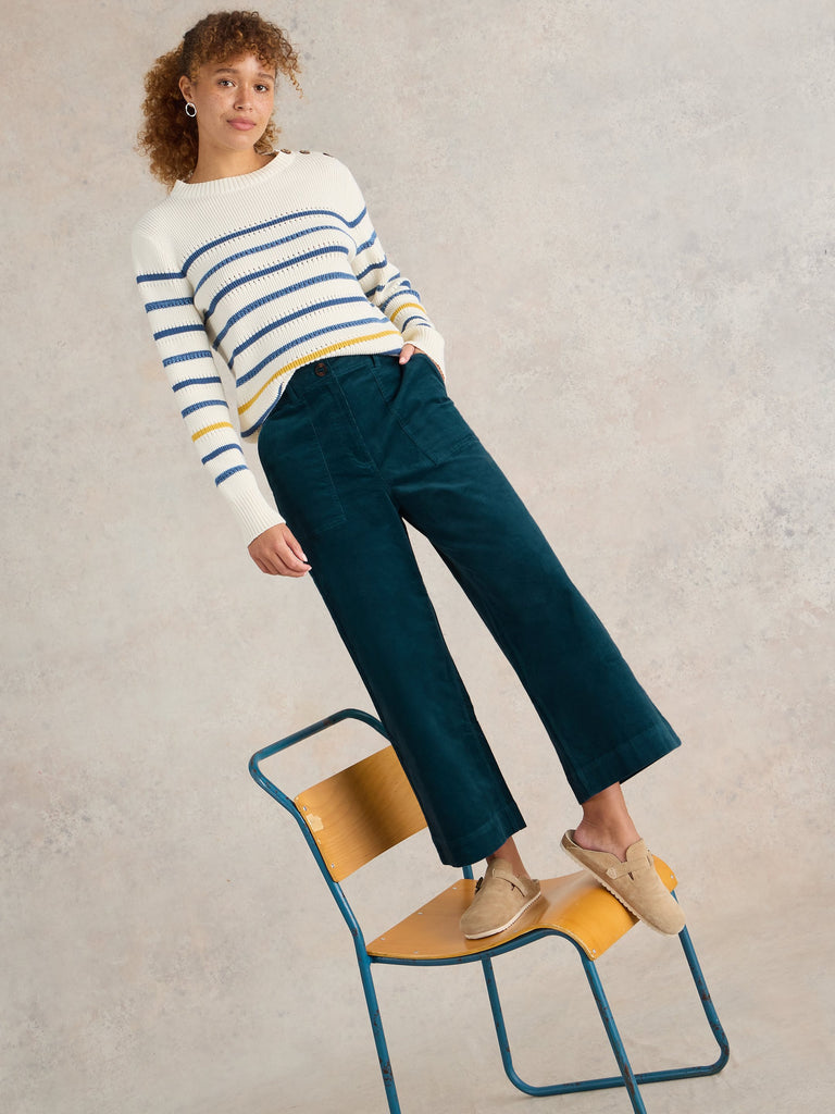 Dark teal corduroy cropped pants with front pockets, modeled with a cream horizontally striped sweater.