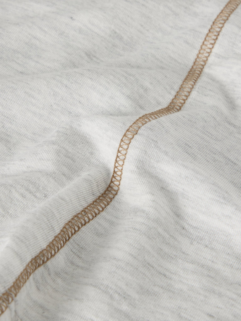 Close-up of light gray fabric with a tan topstitching detail.