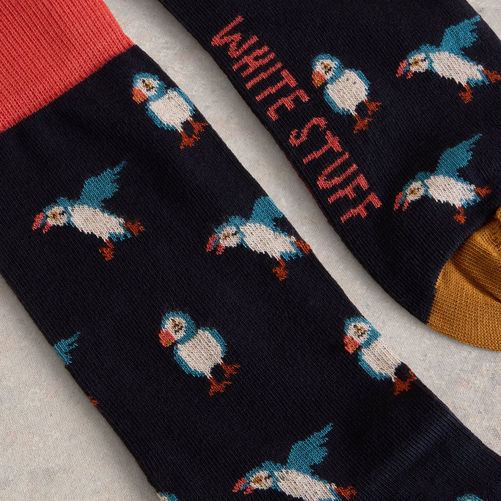 Pair of dark navy blue socks with a repeating puffin pattern and coral and mustard yellow cuffs.