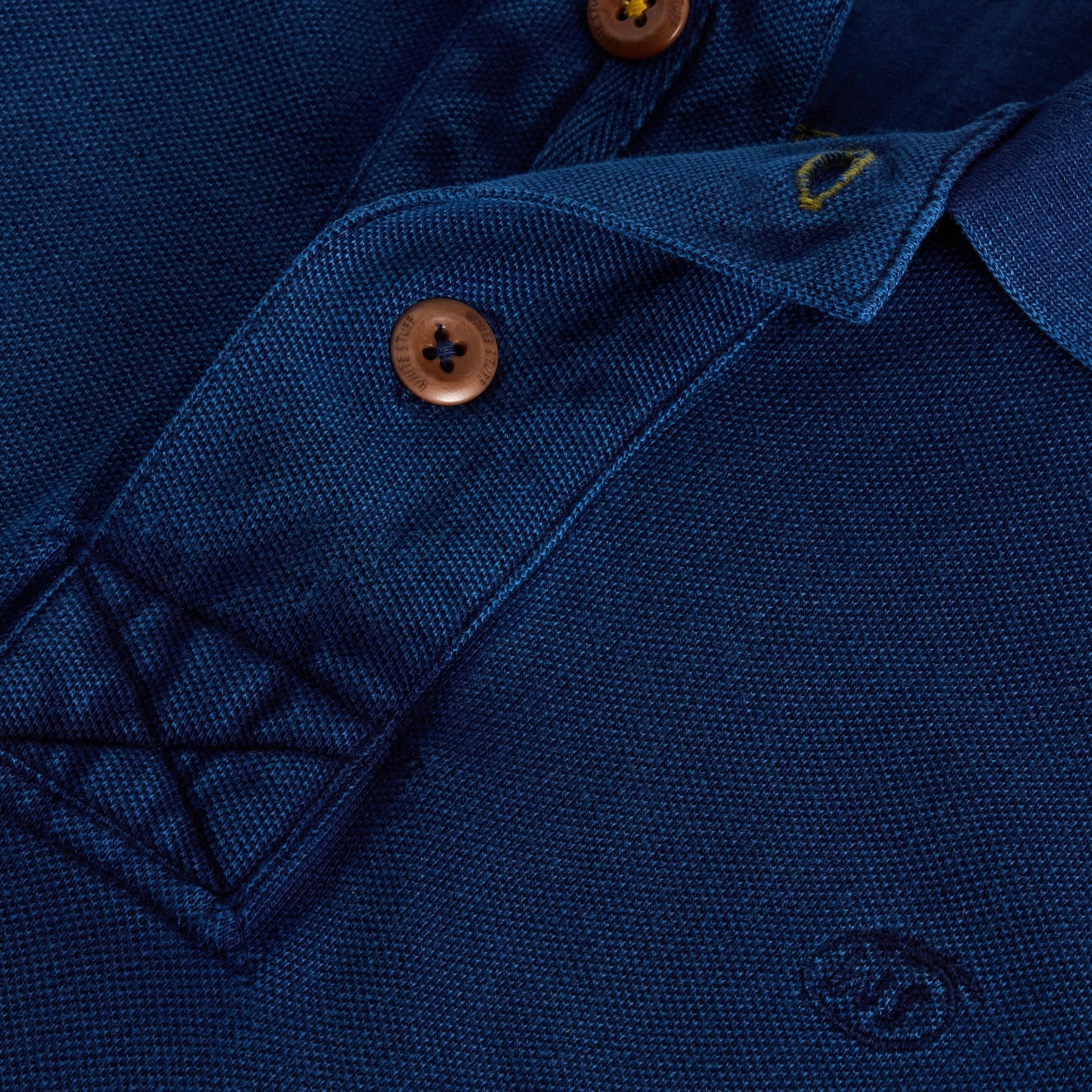 Close-up of a navy blue polo shirt collar, showing textured fabric and brown buttons.