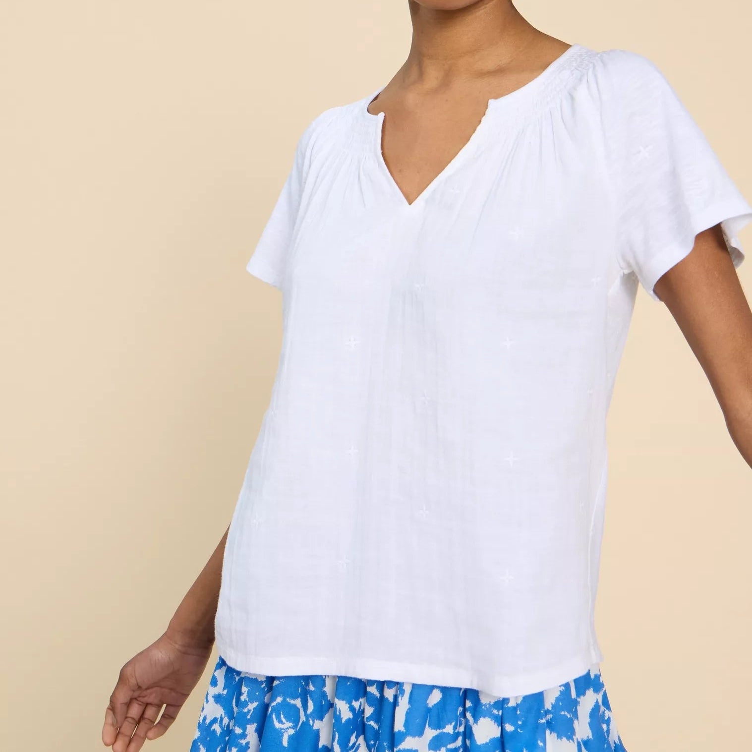 White embroidered cotton top with short sleeves and a V-neck.