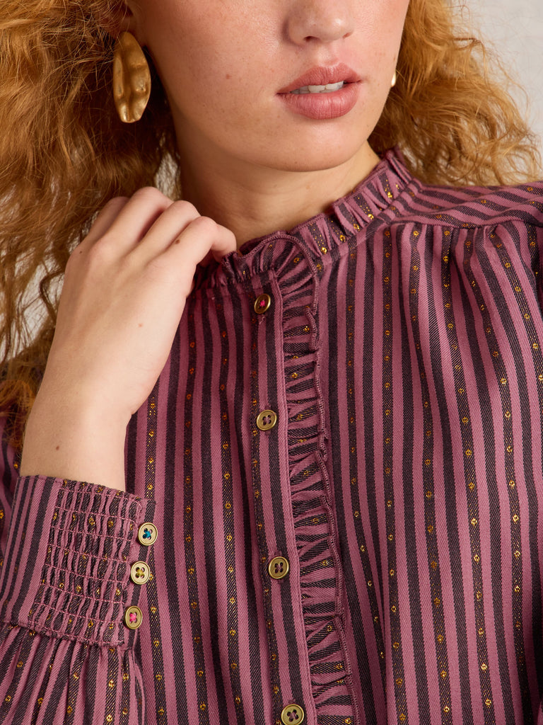 Burgundy and black striped shirt with gold detailing, ruffled neckline, and smocked cuffs. Features decorative buttons.