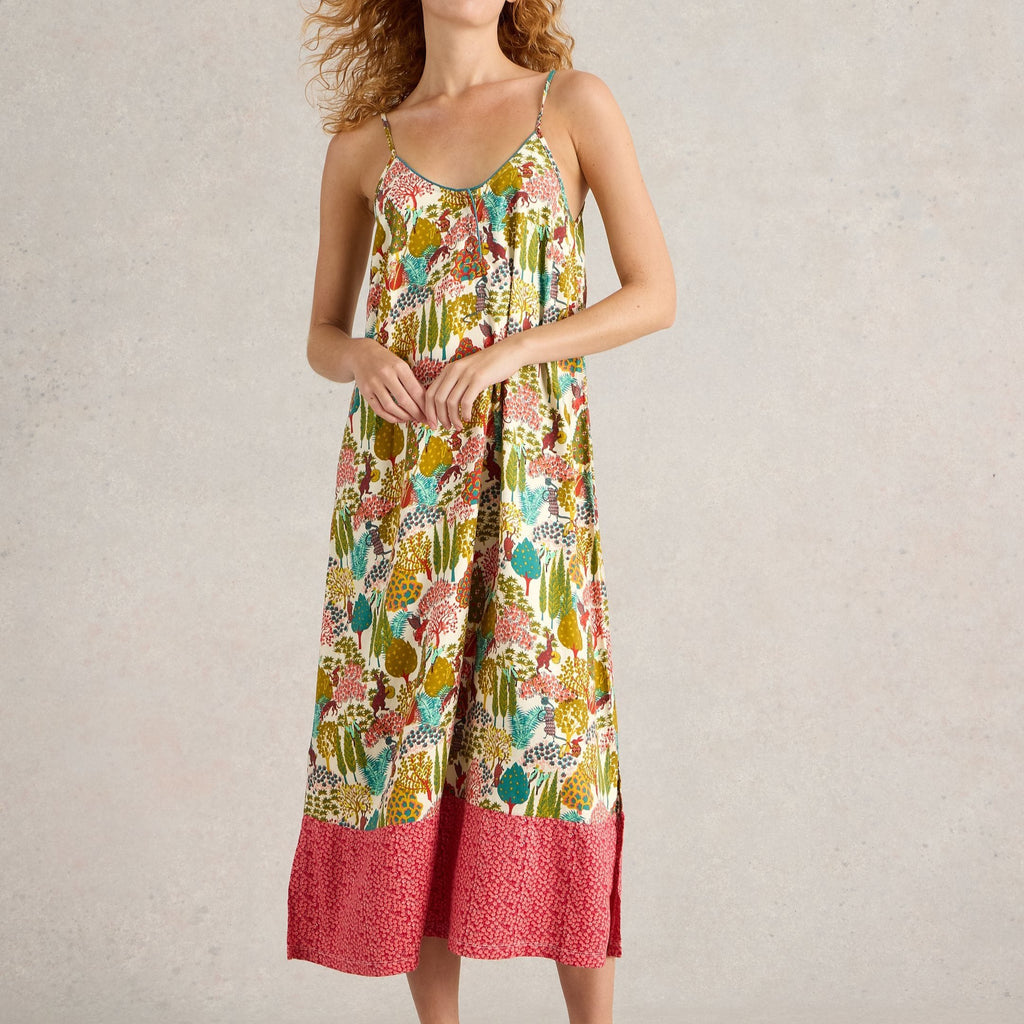 Midi-length sleeveless dress with a whimsical nature-inspired print in greens, oranges, and pinks on a cream background.