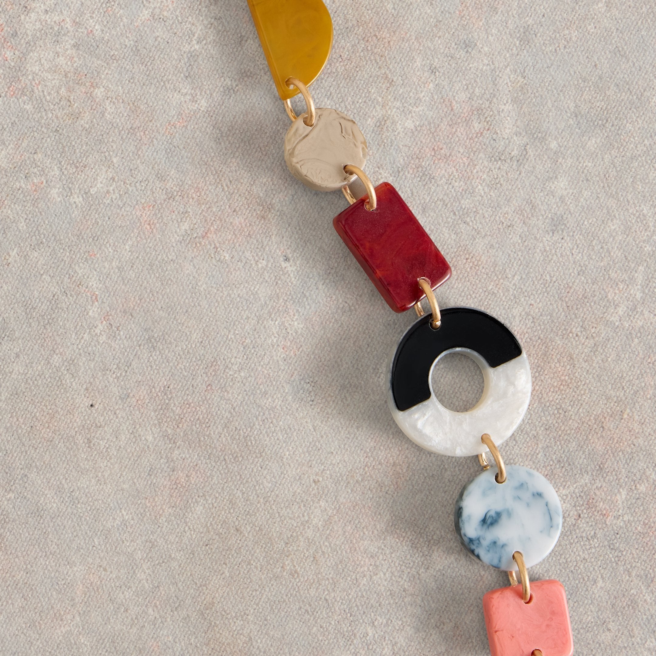 Multicolored resin necklace with gold connectors. Features geometric shapes including circles, squares, and a half-moon.