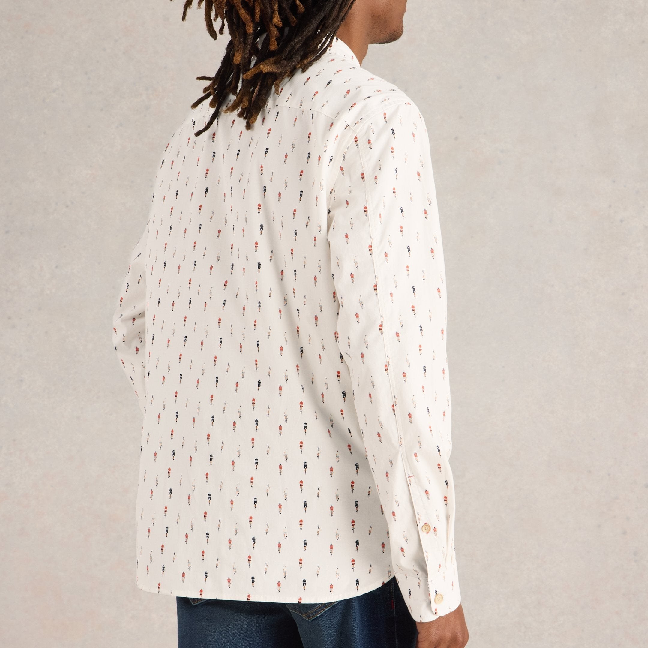 Off-white long-sleeve button-down shirt with a repeating pattern of small, multicolored figures.